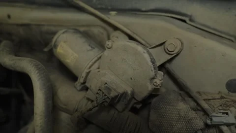 A dusty windshield wiper motor assembly mounted inside engine bay Stock Footage 339685840