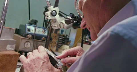 Dutch angle close up shot of a man making a belt buckle in his workshop. Stock Footage 137268101