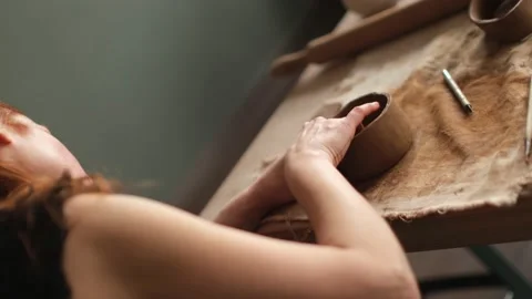 Dutch angle over shoulder shot of ceramic artist sculpting a bowl in the studio Stock Footage 236373180