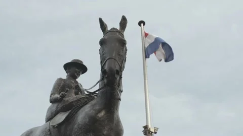 Dutch flag blowing in the wind next to the Queen Wilhelmina statue in Amsterdam Stock Footage 221730914