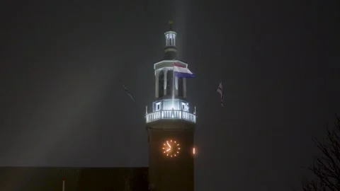 Dutch flag waving on illuminated clock tower at night Stock Footage 323384675