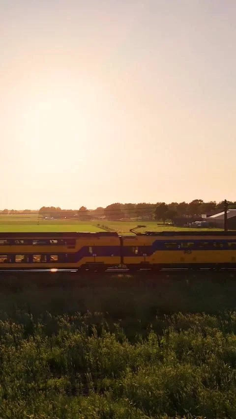 Dutch intercity train passing through countryside at sunset Stock Footage 327109928