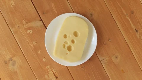 Dutch maasdam cheese slice rotating on a plate Stock Footage 337885763