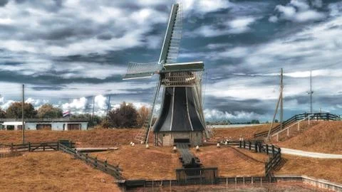 Dutch windmill in a landscape with clouds in the sky Stock Photos