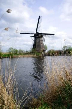 Dutch windmill standing next to polder water. Stock Photos