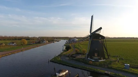 Dutch Windmill surrounded by grass and water during sunset shot by a drone 動画素材 128385793