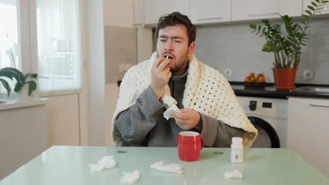 Duvet Comforts Amid Flu Man with Beard Shivers and Wipes Nose, Home Setting in Stock Footage 325734541