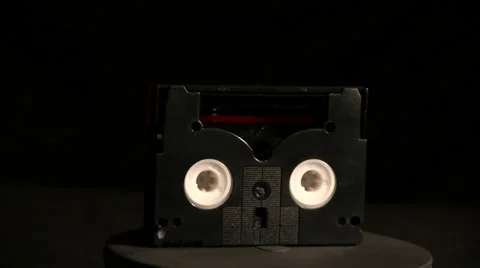 DV cassette rotating against black background Stock Footage 32659575
