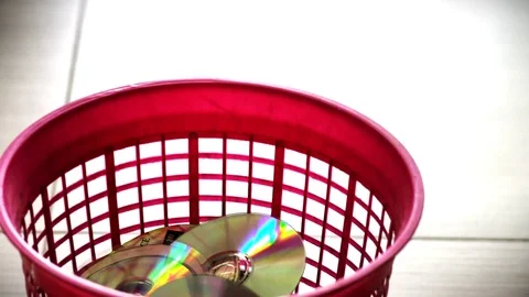 DVD or CD Discs falling in to red trash bin Stock Footage 76691668