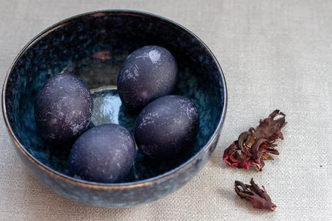 Dyed blue and marble easter eggs in a bowl with hibiscus and carcade Stock Photos