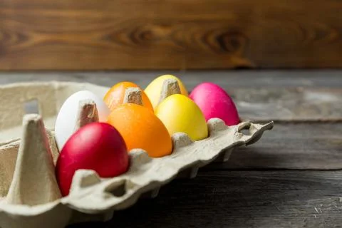 Dyed easter eggs in cardboard box on wooden background. Foto stock