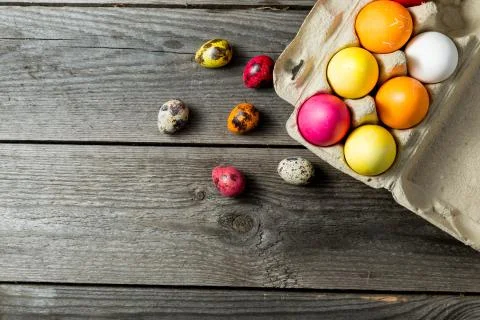 Dyed easter eggs in cardboard box on wooden background. Stock Photos