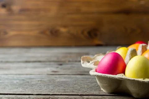 Dyed easter eggs in cardboard box on wooden background. Foto stock