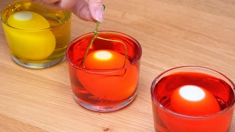 Dyeing Easter eggs color at home kitchen table for Easter celebration. Stock Footage 124400946