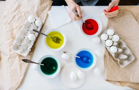 Dyeing Easter eggs with liquid food coloring. Different colors in different Stock Photos