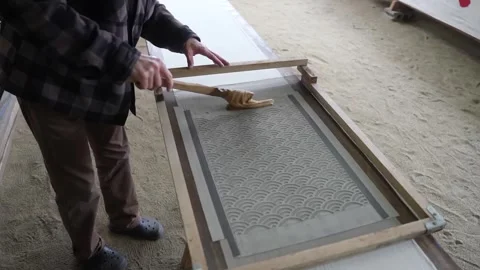 Dyer crosses a sand floored workshop with a wooden spatula and sets a wave Stock Footage 342319634