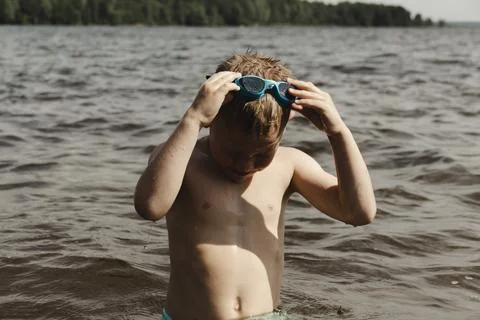 A dynamic action shot of a young boy in shallow water actively putting on blu Фото