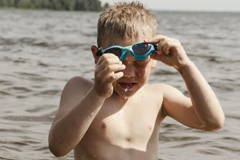 A dynamic action shot of a young boy in shallow water actively putting on blu Photos