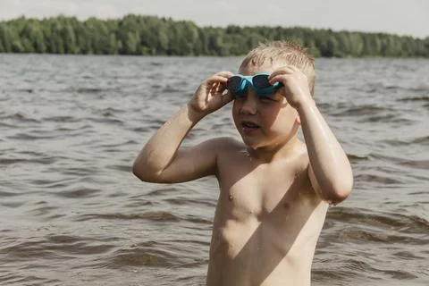 A dynamic action shot of a young boy in shallow water actively putting on blu Stockfoto's