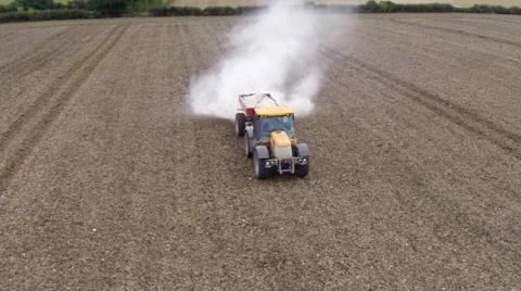 Dynamic aerial flyover of a tractor fertilizing a field Stock Footage 46858852