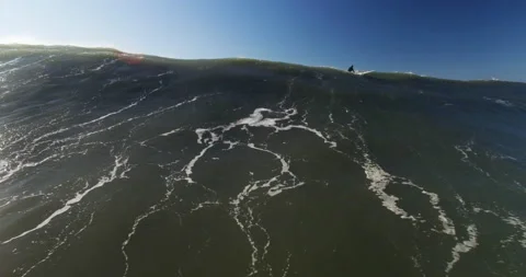 Dynamic aerial of massive ocean wave splashing around in ocean with surfers near Stock Footage 155664914