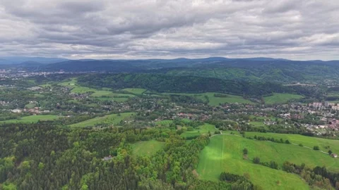 Dynamic aerial panorama over rolling green hills, patchwork farmland, and small Stock Footage 346261764