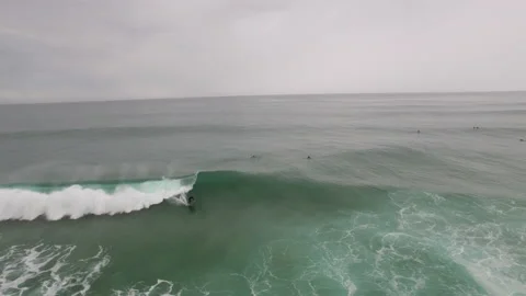 Dynamic aerial of pro surfer riding on fast ocean wave near sandy shore Stock Footage 156000958