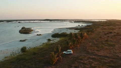 Dynamic aerial shot of all-terrain SUV with a rooftop tent riding through Stock Footage 231454175