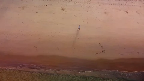 Dynamic aerial shot of individual running along golden Phuket beach coast in Stock Footage 344085964
