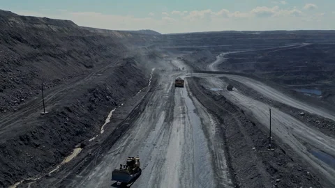 Dynamic aerial view of active machinery on a coal mine road between rugged Stock Footage 275009185