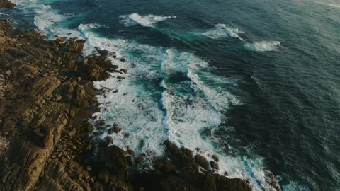 Dynamic aerial view of deep blue Atlantic waves surging against dark, jagged Stock-Footage 336286588