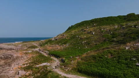 Dynamic aerial view of a group of cyclists navigating a scenic coastal trail 動画素材 336286096