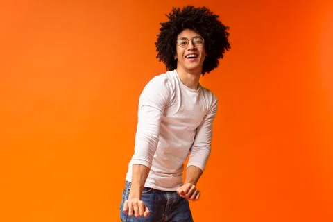 Dynamic african guy dancing on orange background 写真素材