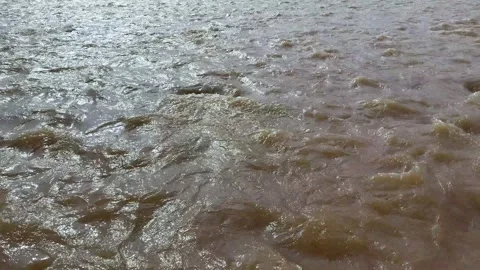 Dynamic brown river water surface with ripples and reflections under natura.. Vidéo 339295948