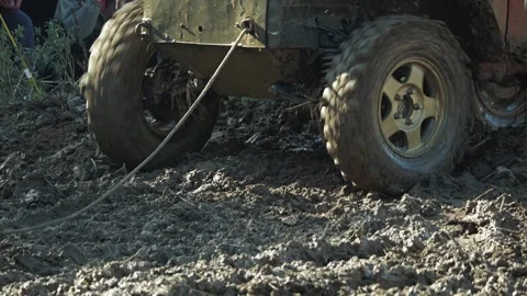 Dynamic close-up of a 4x4 vehicles spinning wheels struggling in deep mud Stock Footage 345495317