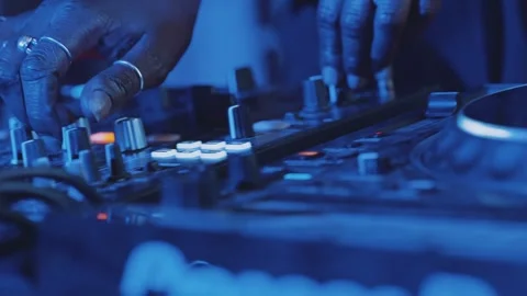 Dynamic close-up of female DJ hands adjusting mixer knobs during a live Stock Footage 325830612