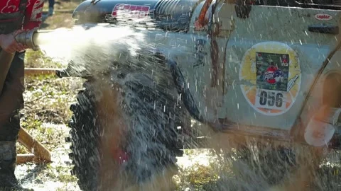 Dynamic close-up of a race team member cleaning a dirty offroad buggy Stock Footage 345494673