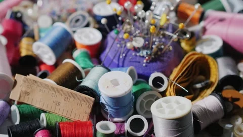Dynamic close up of sewing threads, pins and notions scattered on white sur.. Stock Footage 334991751