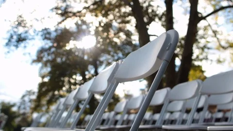 Dynamic close shot of white folding chairs outside with sun shining Stock Footage 96544271