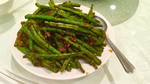 Dynamic close-up of vibrant green beans with savory sauce, a classic Asian dish Video stock 318311143