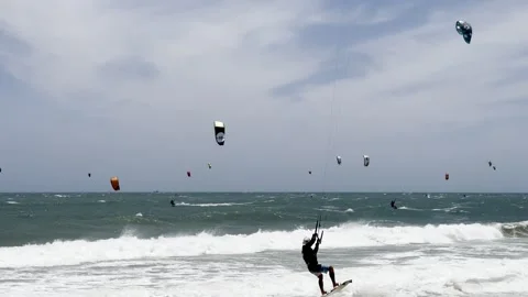 A dynamic coastal scene showing numerous kiteboarders catching waves on a b.. Stock Footage 337354312
