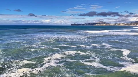 Dynamic coastal waves beneath clear sky. Energetic oceanfront with rolling surf Stock Footage 342360936