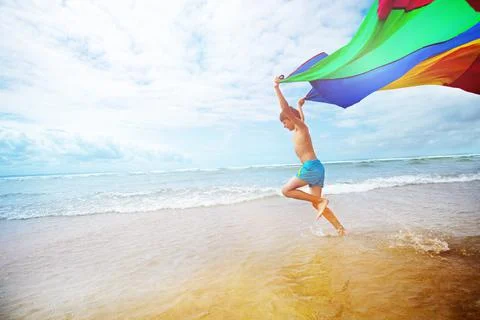 Dynamic concept boy run on beach with fabric fly Foto stock