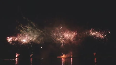 Dynamic continuous fireworks displaying across ocean water with reflections Video stock 340744807