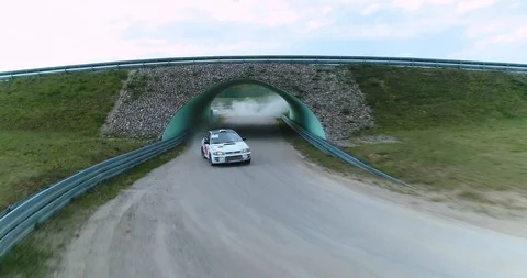 Dynamic dolly drone shot of car riding out of tunnel on a race track. Stock Footage 89416257