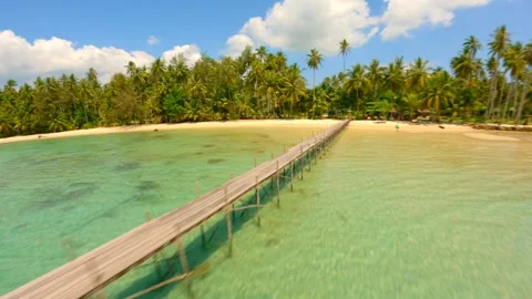 A dynamic drone flight over turquoise ocean, wooden bridge and white sand beach. Stock Footage 240119619