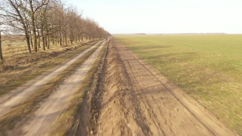 Dynamic drone fly above dirt road near a field towards to red motorcycle Stock Footage 152789585