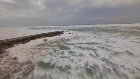 Dynamic drone shot captures powerful waves breaking on coastal defense structure Stock Footage 345050771