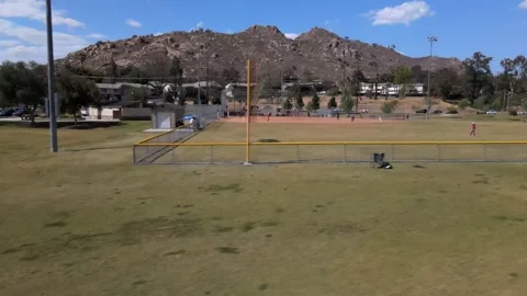 A dynamic drone shot circles a minor league baseball field mid-play, Stock Footage 244692685
