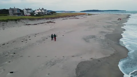 Dynamic drone shot of a young couple walking along Maine beach at sunset. Stock Footage 339825596